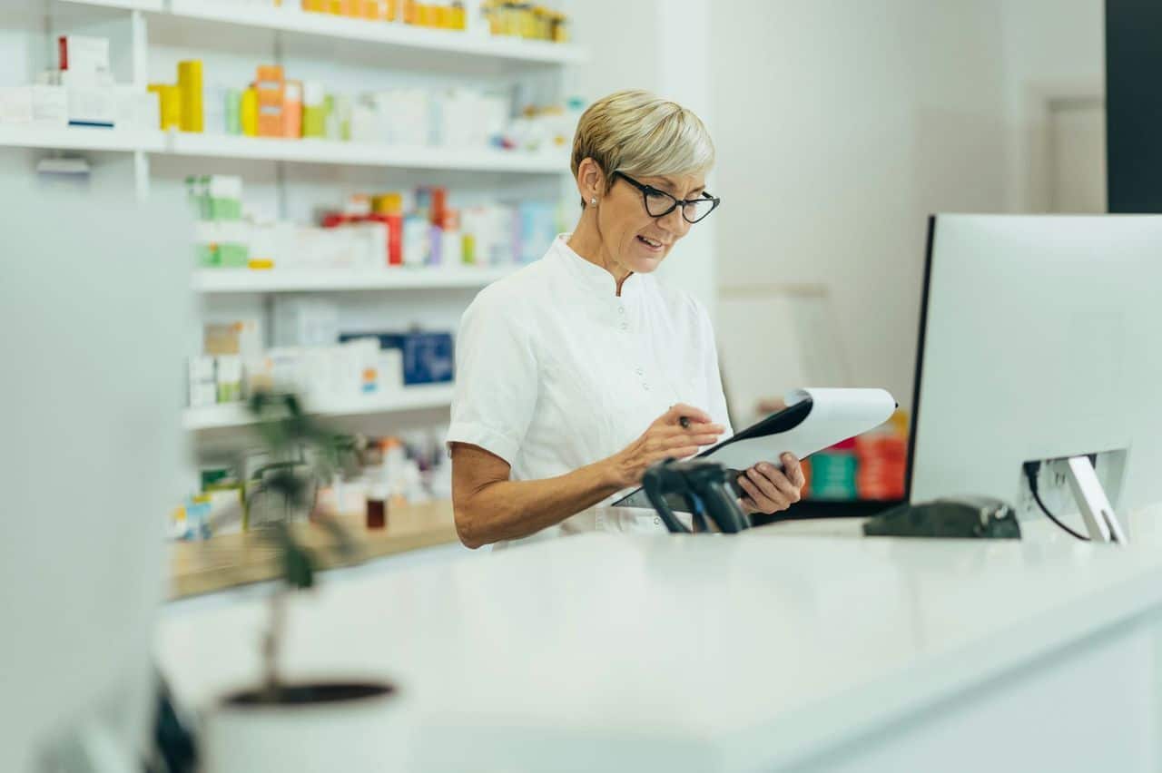 A healthcare leader or pharmacy program manager reviewing analytics on a digital dashboard — ideally with charts, claims data, or network visuals on a laptop or tablet.